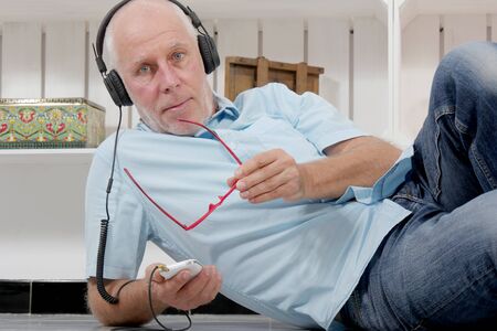 handsome mature man listening to music with headphones at home