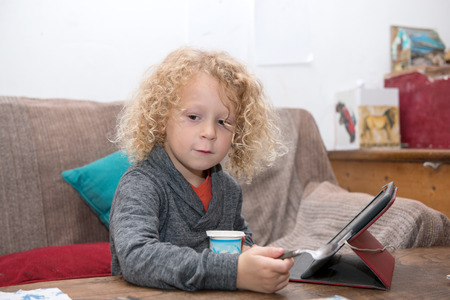little blond boy using tablet computer at homeの写真素材