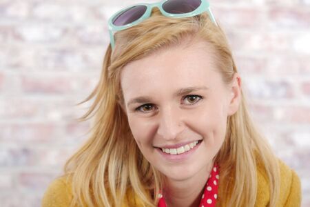 beautiful young blonde  woman with a yellow jacket and sunglassesの写真素材