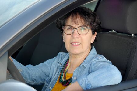 smiling brunette mature woman driving car