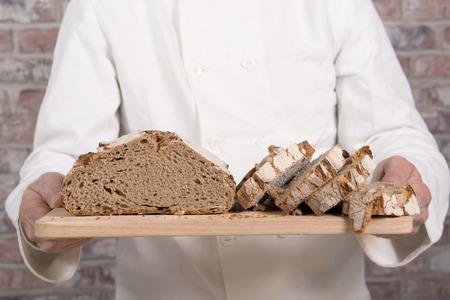 a baker hands with fresh bread on wood table