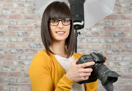 Attractive smiling brunette woman with photo cameraの写真素材
