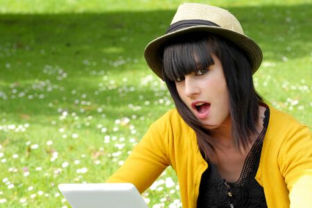 portrait of young brunette girl with a tablet in park, outside