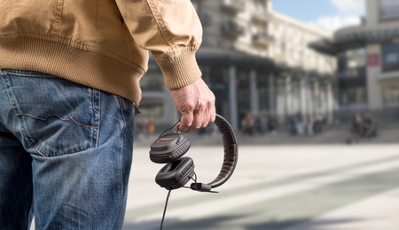 man holding headphones in his hand in the cityの写真素材