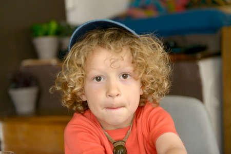 portrait of blond and curly  boy with a blue capの写真素材