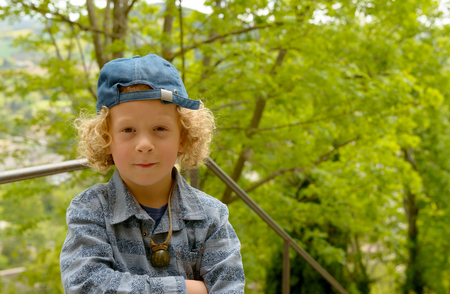 portrait of blond and curly  boy with a blue capの写真素材
