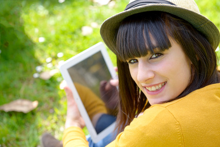 portrait of young brunette girl with a tablet in park, outsideの写真素材