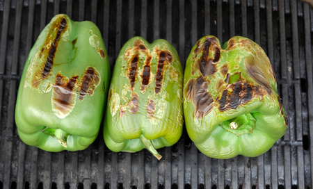 three green peppers grilling on the barbecueの写真素材