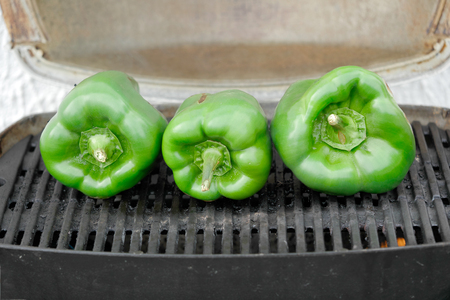 three green peppers grilling on the barbecueの写真素材