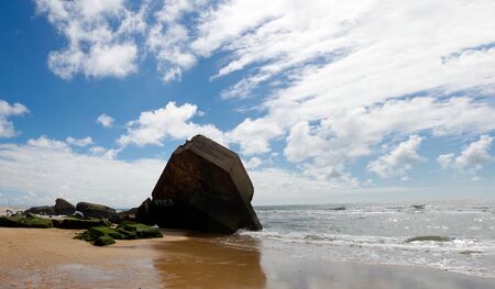 a blockhouse on the beach with blue sky and cloudsの写真素材