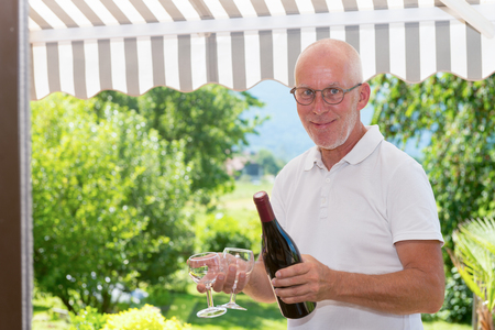 mature man with a bottle of red wine, on the terrace