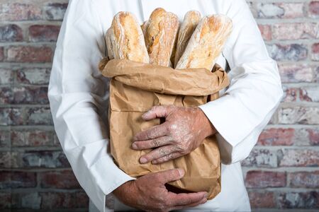 a baker holding  traditional bread french baguettes