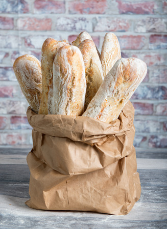the fresh baked rustic bread loaves in paper bagsの写真素材
