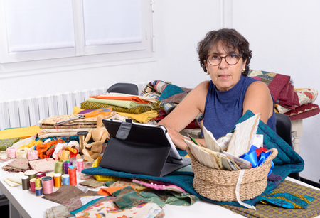 a beautiful mature seamstress using tablet computerの写真素材