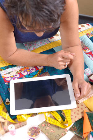 a beautiful mature seamstress using tablet computer