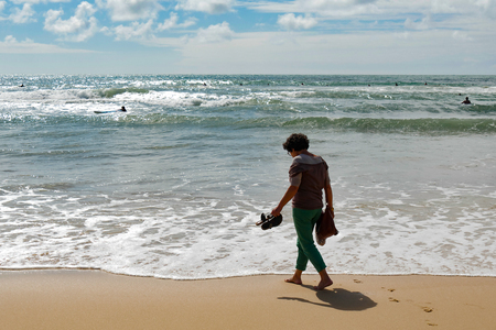 a mature woman walking on the beachの写真素材