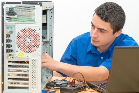 a young technician working on broken computer in his officeの写真素材