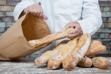 a baker holding traditional bread french baguettesの写真素材
