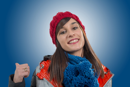 a young smiling brunette woman with a red winter capの写真素材