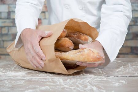 a baker holding traditional bread french baguettes