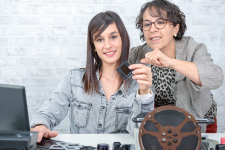 two women looking at old film slideの写真素材