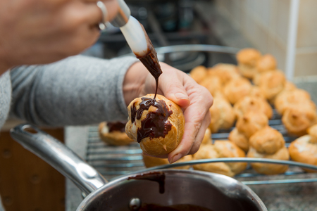 the preparation of small cream puffs with chocolateの写真素材