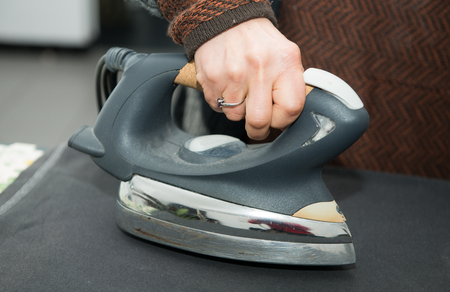 a woman ironing a black clothe, close-upの写真素材