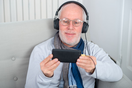 happy senior man in headphones listening to music at homeの写真素材