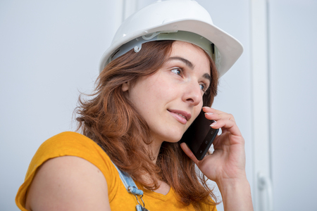 Young engineer woman with a safety helmet talking on phoneの写真素材