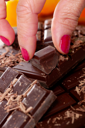 tablet and pieces of dark chocolate with the woman fingerの写真素材