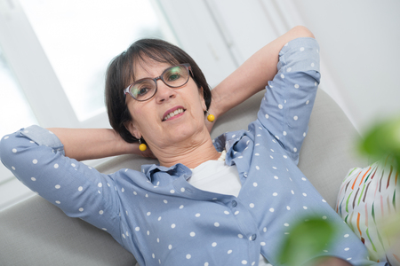 brunette mature woman relaxes in the sofa at homeの写真素材