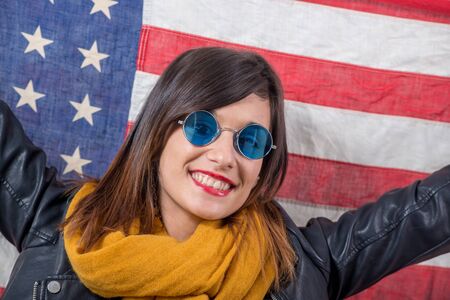 a young brunette with blue sunglasses in front of  american flagの写真素材