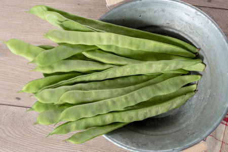 A bunch of flat beans on a wooden board.