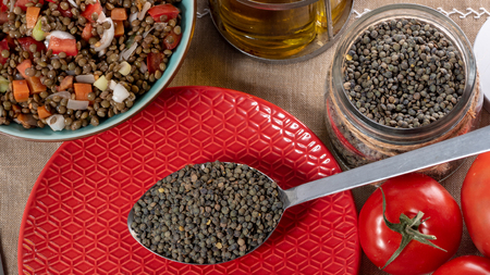 the green lentils in a spoon in red plateの写真素材