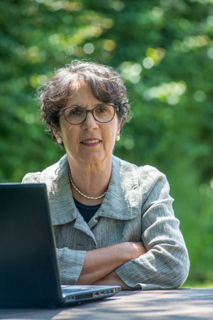a mature brunette using laptop in the gardenの写真素材