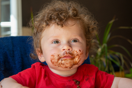a baby is eating a chocolate cakeの写真素材
