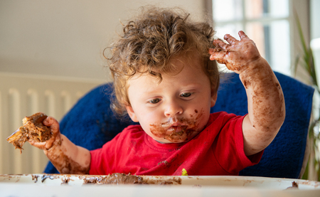 a baby is eating a chocolate cakeの写真素材