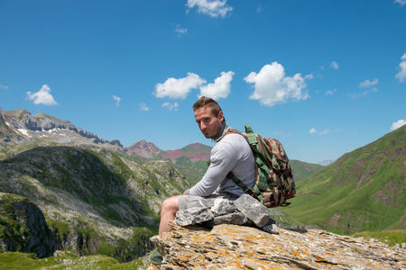 a young man hiker sitting on a rock in mountainの写真素材