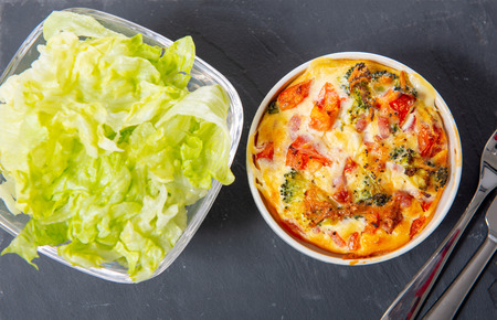 a french quiche lorraine with salad in small white bowls