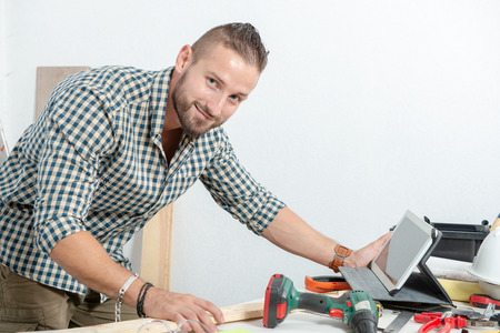 a smiling young man at home with tablet