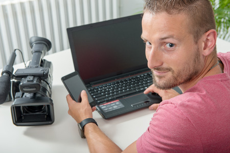 a young video editor with laptop and video camera