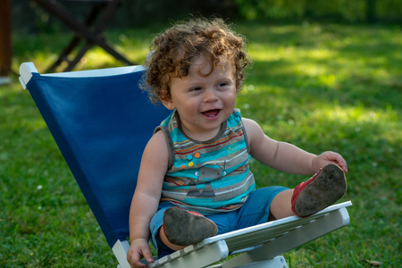a smiling little boy sitting in the gardenの写真素材