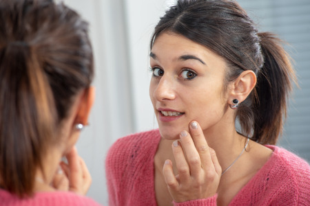a young brunette woman puting makeup in the mirrorの写真素材