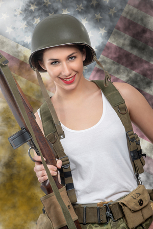pretty young woman dressed in wwii military uniform with a helmet and rifleの写真素材