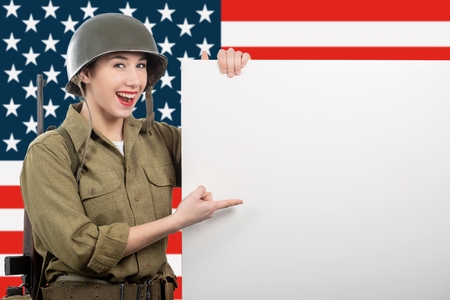 young woman dressed in American ww2 military uniform showing empty blank signboard with copy spaceの写真素材