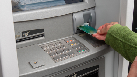Hand of a woman with a credit card, using an ATM