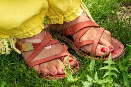 a close-up of woman's feet with sandals in the grassの写真素材
