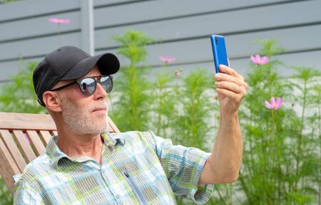 a senior man in a baseball cap portrait making selfie