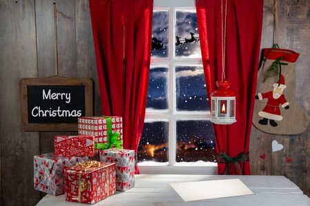 Christmas gifs decoration near the rustic window. Santa Claus with sled in the skyの写真素材