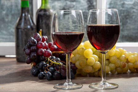 Composition with two wineglasses, grapes and bottles of a red wineの写真素材